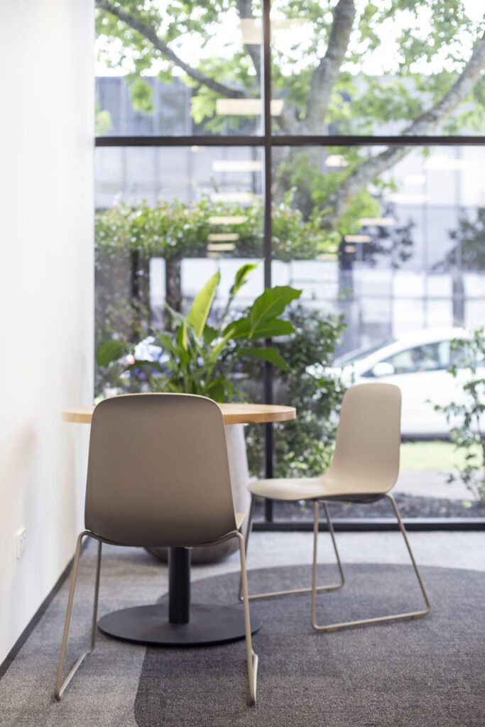 Jac chairs for a breakout space where casual meetings can happen. They are rey in colour and the background has greenery to bring biophilic element to the space.